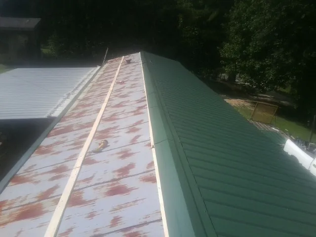 Old rusted panels beside newly installed green metal roofing — Wind Damage Roof Repair by Roofing Brothers in Statesville