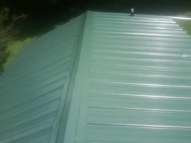 New green metal panels meeting at the ridge of a roof — Flat Roof Repair work by our crew in Statesville