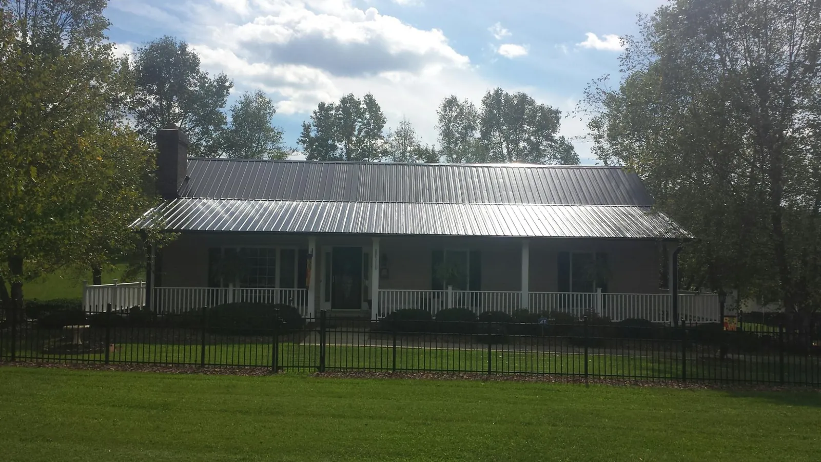 Gray metal roof on a brick ranch with a full width front porch — Gutter Guard Installation work by our crew in Statesville