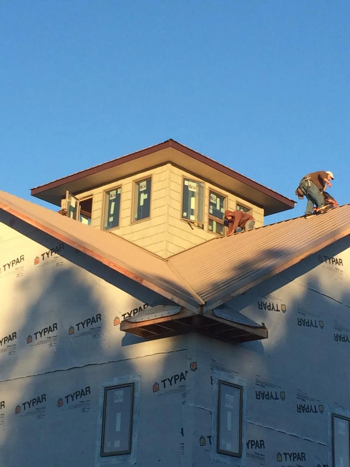 Roofers working around a rooftop cupola on a new metal roof at sunset — Roof Waterproofing in Statesville by Roofing Brothers